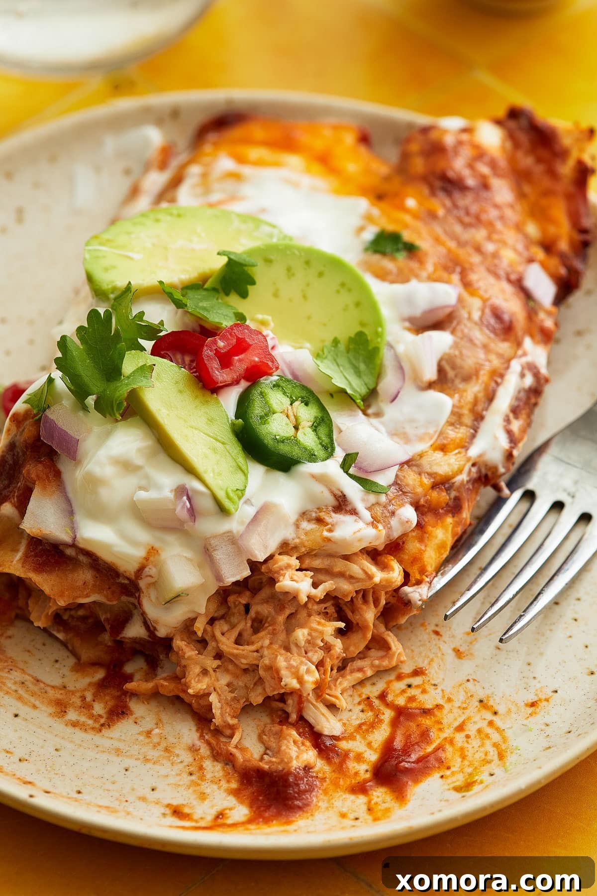 Effortless Cheesy Chicken Enchiladas 7 A fully prepared baking dish of chicken enchiladas with various toppings on the side.