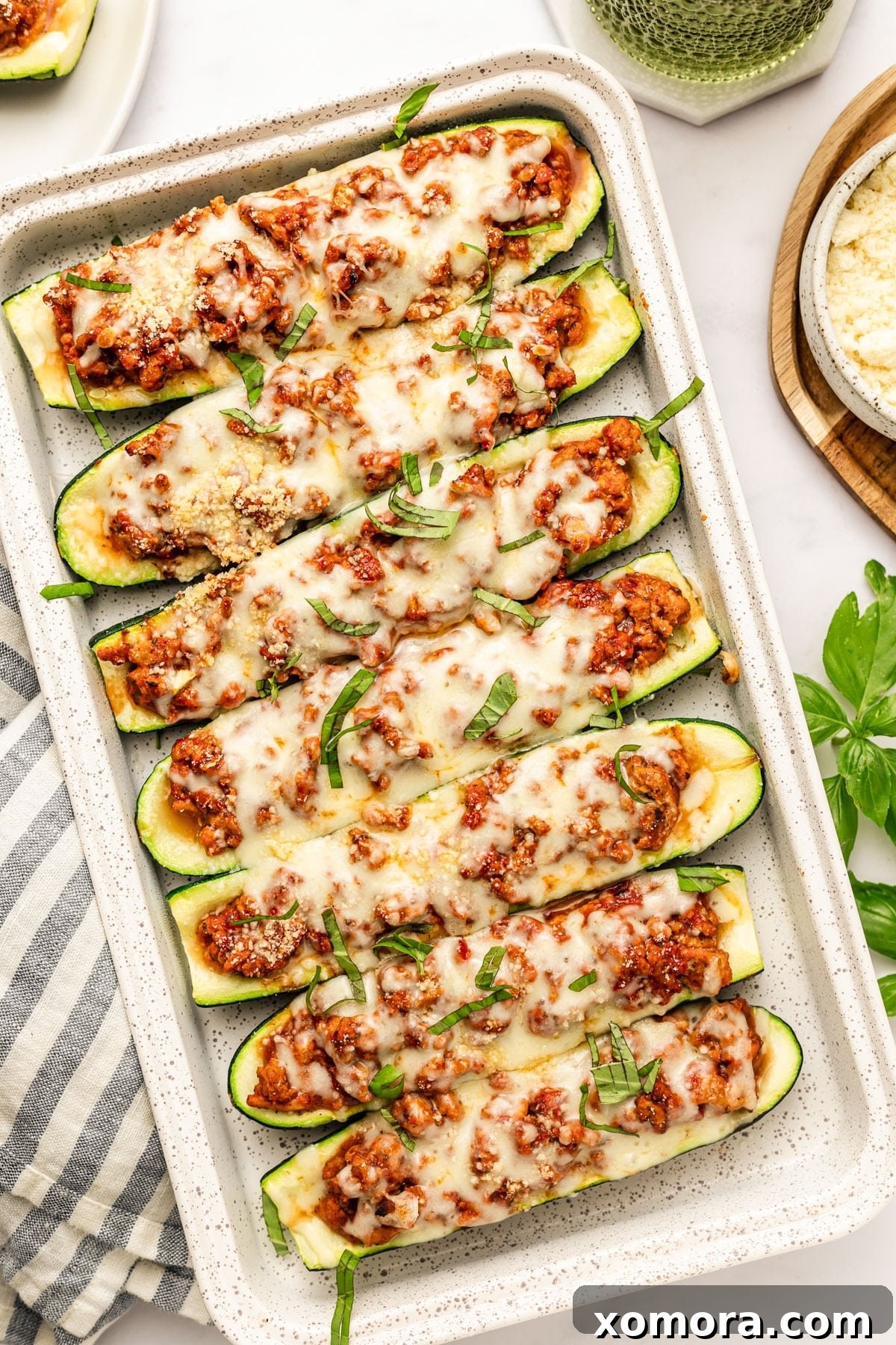 Stuffed Zucchini Boats with Turkey Lasagna 2 Close-up of baked turkey lasagna zucchini boats topped with melted cheese and fresh herbs, sitting in a baking dish.