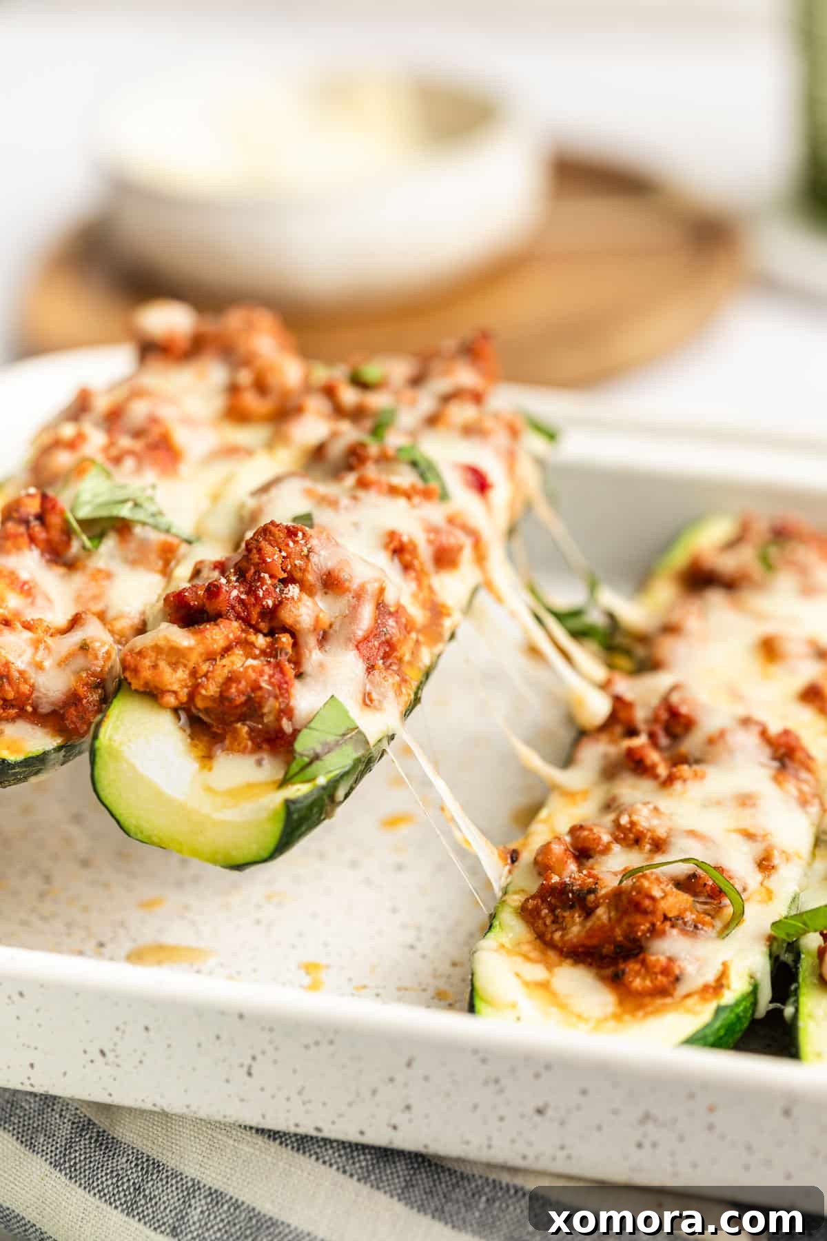 Stuffed Zucchini Boats with Turkey Lasagna 6 A single turkey lasagna zucchini boat on a white plate, garnished with fresh basil.