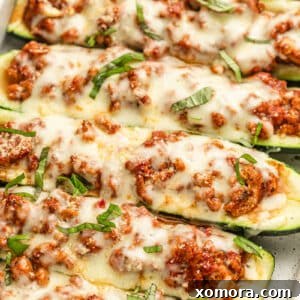 Stuffed Zucchini Boats with Turkey Lasagna 7 A wide shot of several turkey lasagna zucchini boats in a white baking dish.