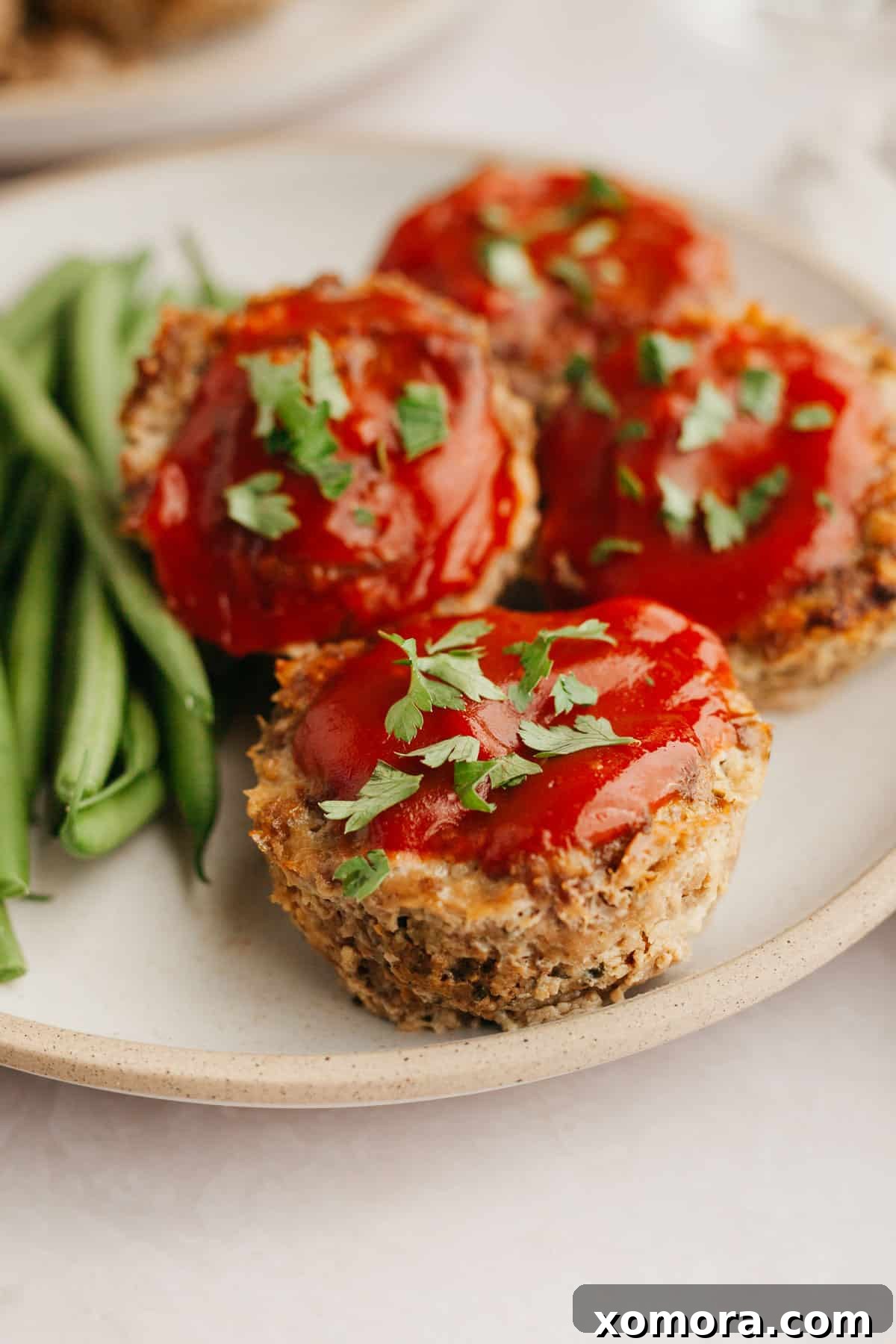 Savory Meatloaf Cups 6 Several Meatloaf Muffins arranged on a plate, garnished with fresh herbs, ready to be served.