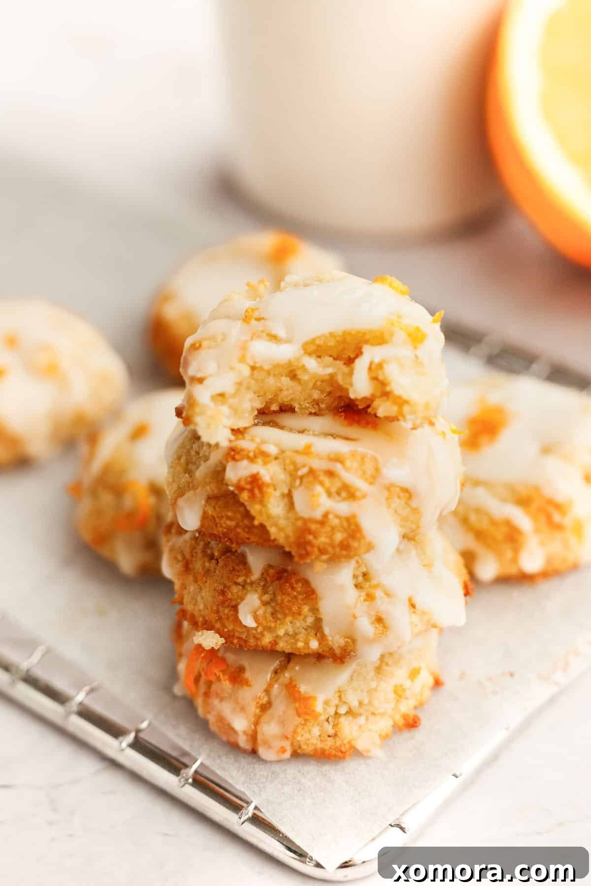 Zesty Orange Almond Delights 2 A stack of golden-orange almond cookies, perfectly round and glazed, with a vibrant orange zest garnish.