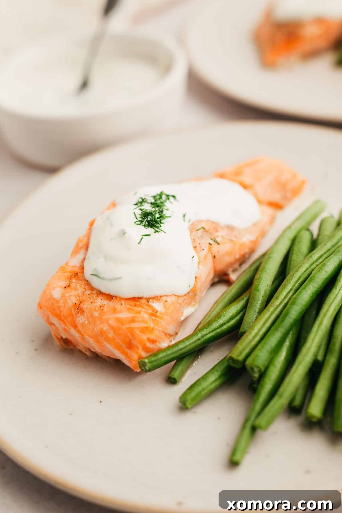 Deliciously Simple Lemon Dill Oven Salmon 2 Perfectly baked salmon fillets with creamy lemon dill sauce, garnished with fresh dill.