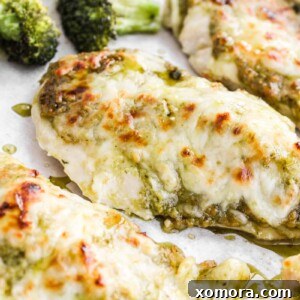 Close-up of baked pesto chicken with melted mozzarella and broccoli