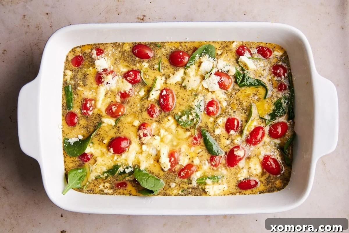 A freshly baked low carb feta breakfast casserole, glistening with cheese and ready to be sliced, in a 9x13 inch baking dish.