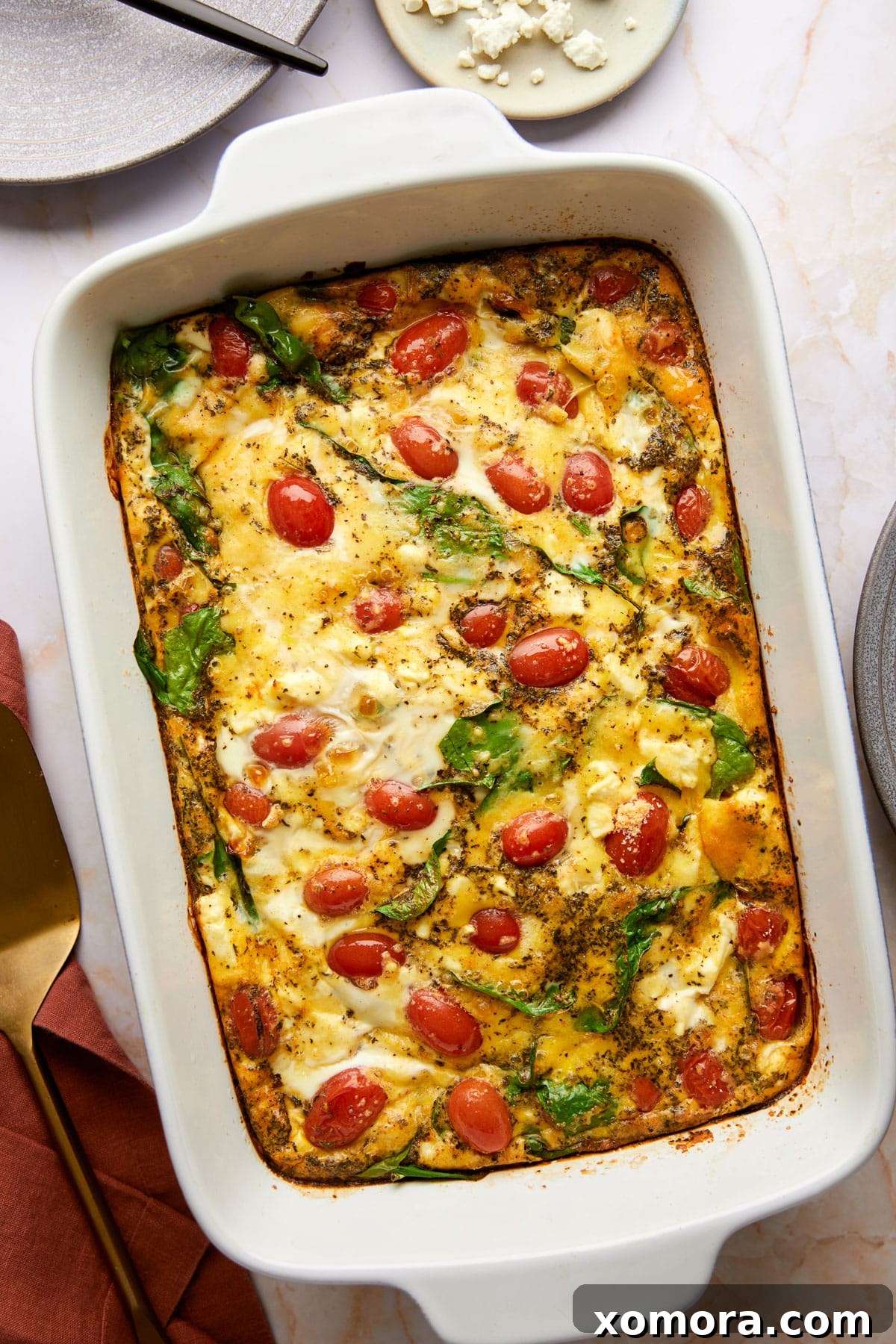 A close-up of a single slice of low carb feta breakfast casserole, showcasing the texture, cheese, spinach, and tomatoes.