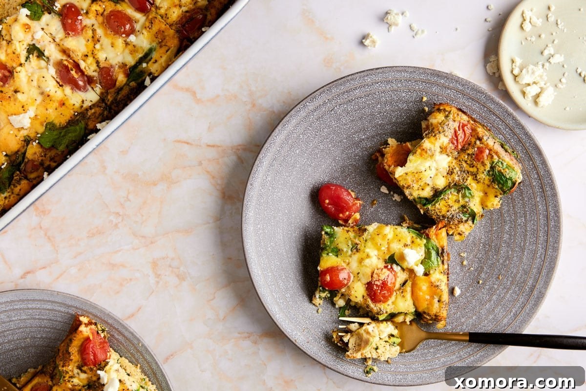 The entire low carb feta breakfast casserole in a baking dish, cut into 8 square slices, with one slice removed to show the fluffy interior.