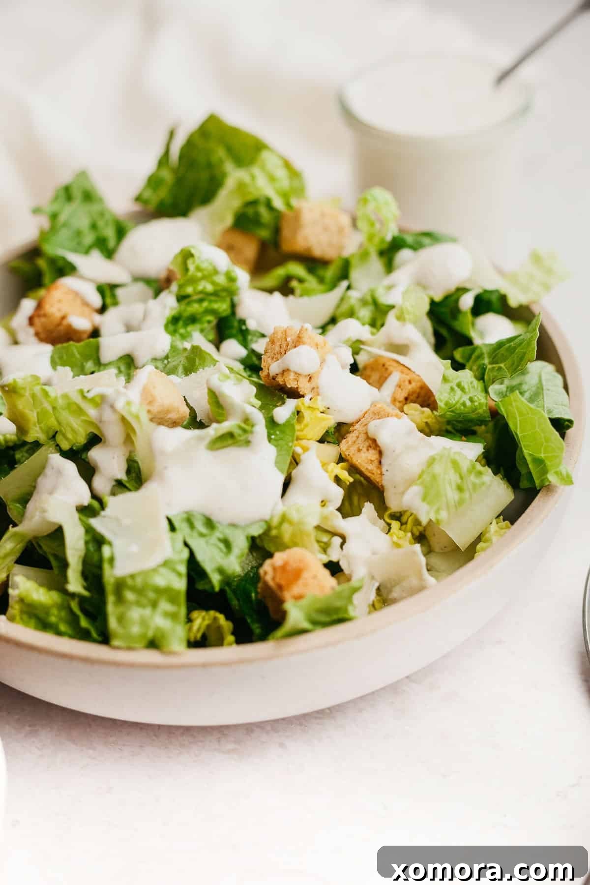 Quick Healthy Caesar Dressing Anchovy-Free 5 A close-up shot of a Caesar salad with dressing, Parmesan, and black pepper.
