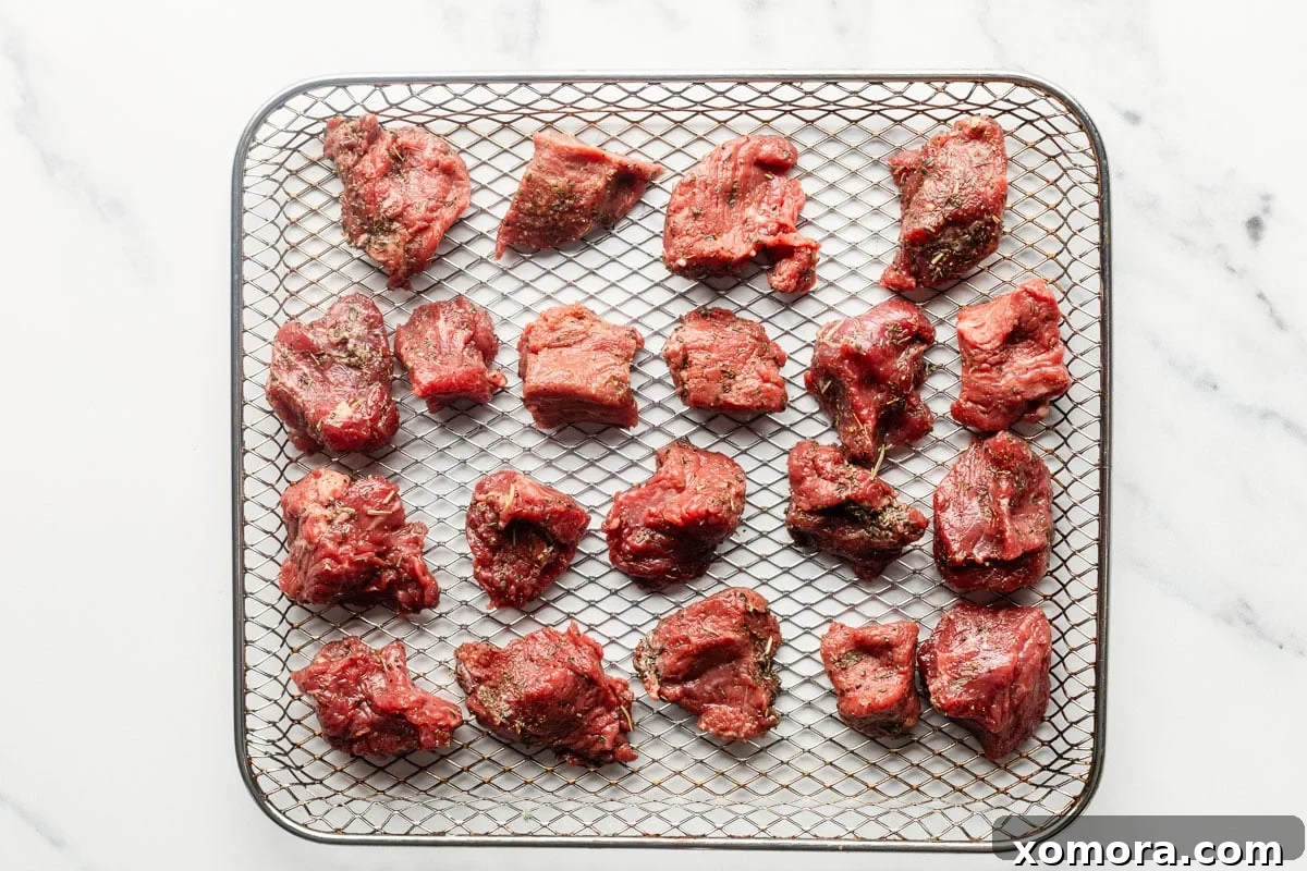 Cooking air fryer steak bites in a preheated air fryer basket.