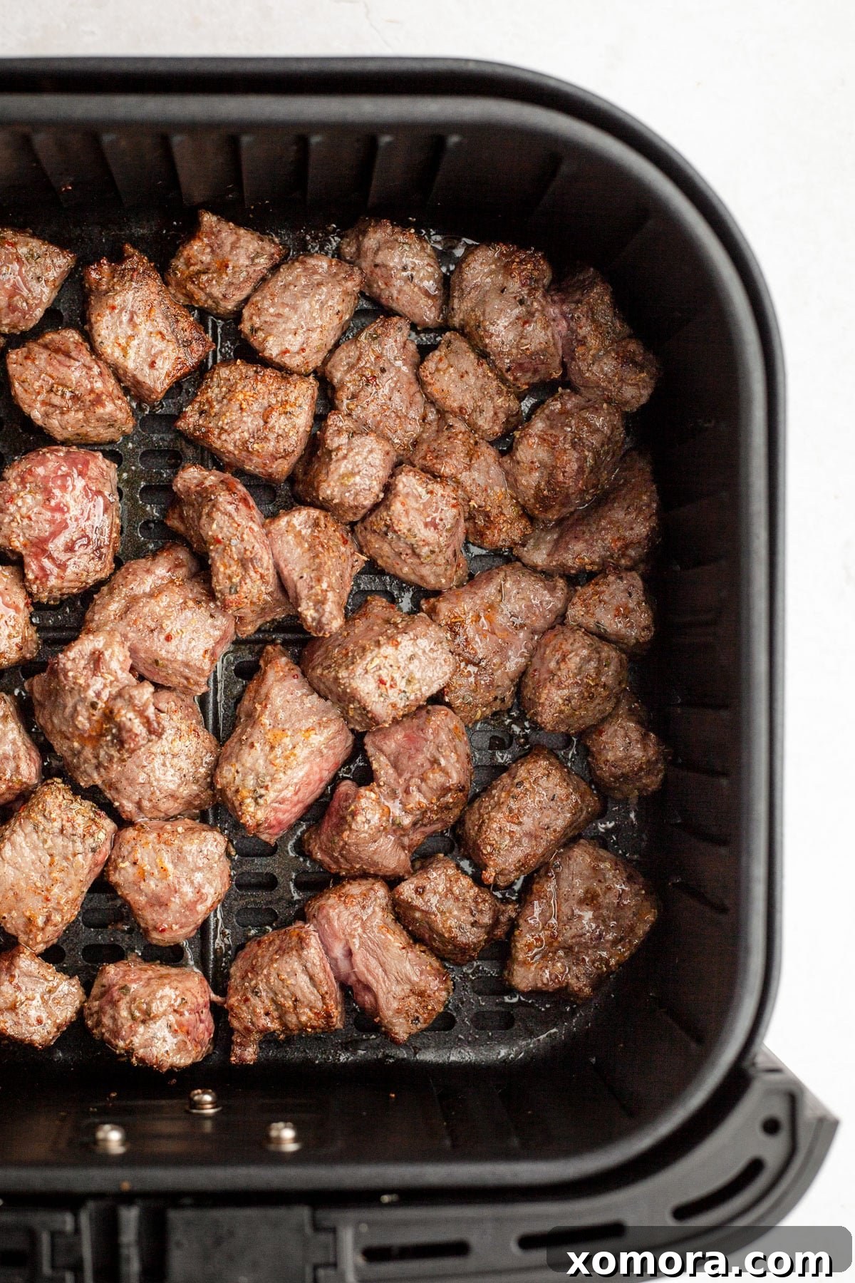 Cooked air fryer steak bites garnished with fresh herbs.