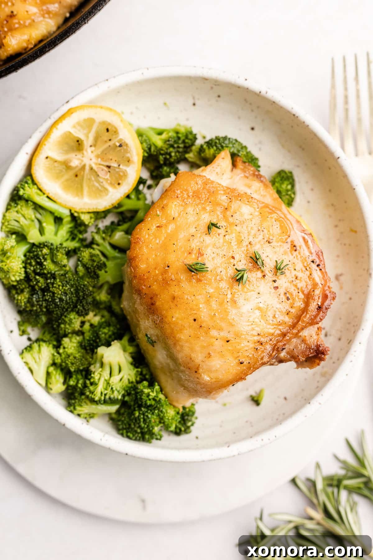 Zesty Lemon Roasted Chicken Thighs 4 Close-up of fresh rosemary, oregano, and thyme sprigs gathered on a wooden surface, highlighting their vibrant green colors.