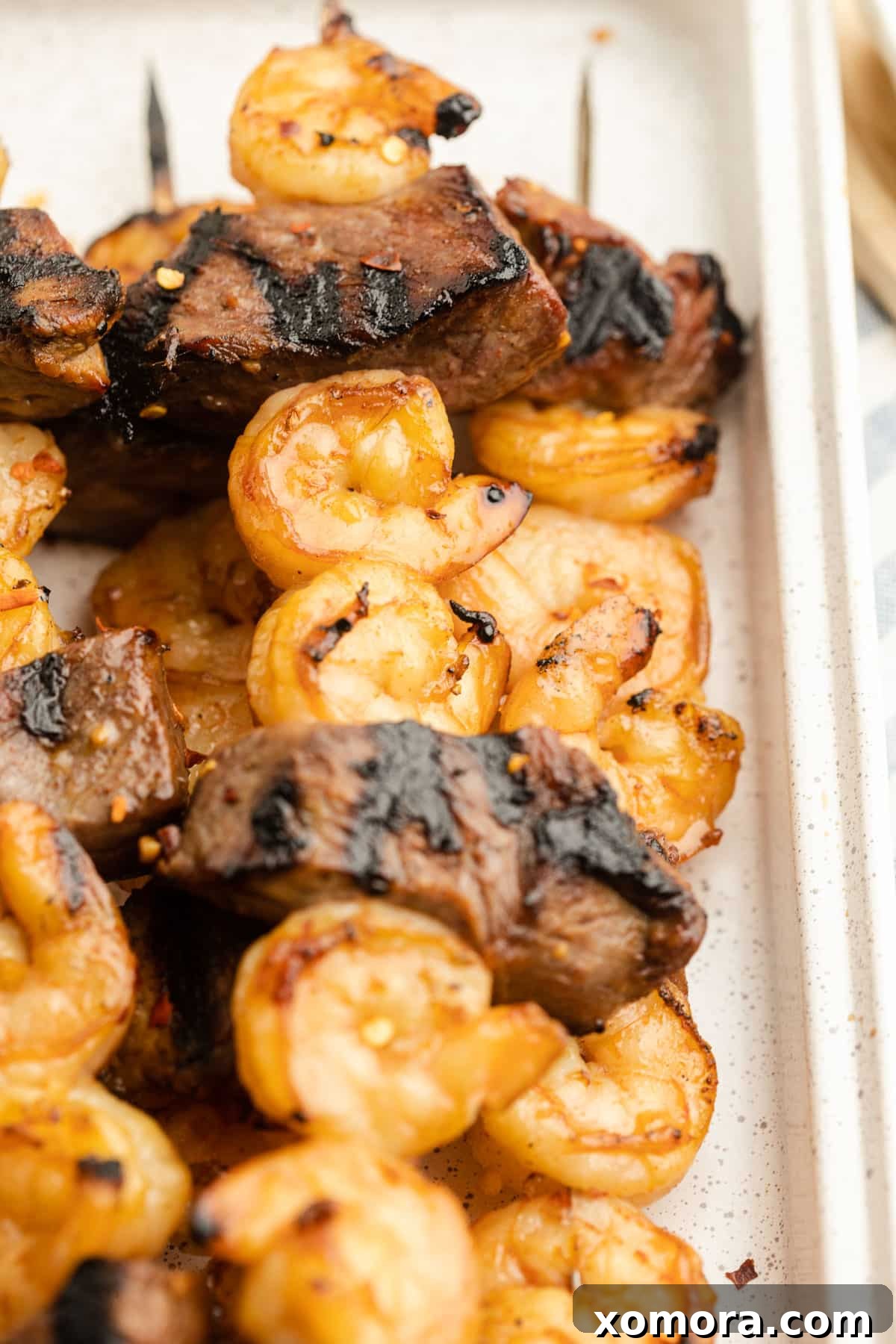 Surf and Turf Skewers 2 Perfectly grilled steak and shrimp kabobs on a platter, ready to be served.