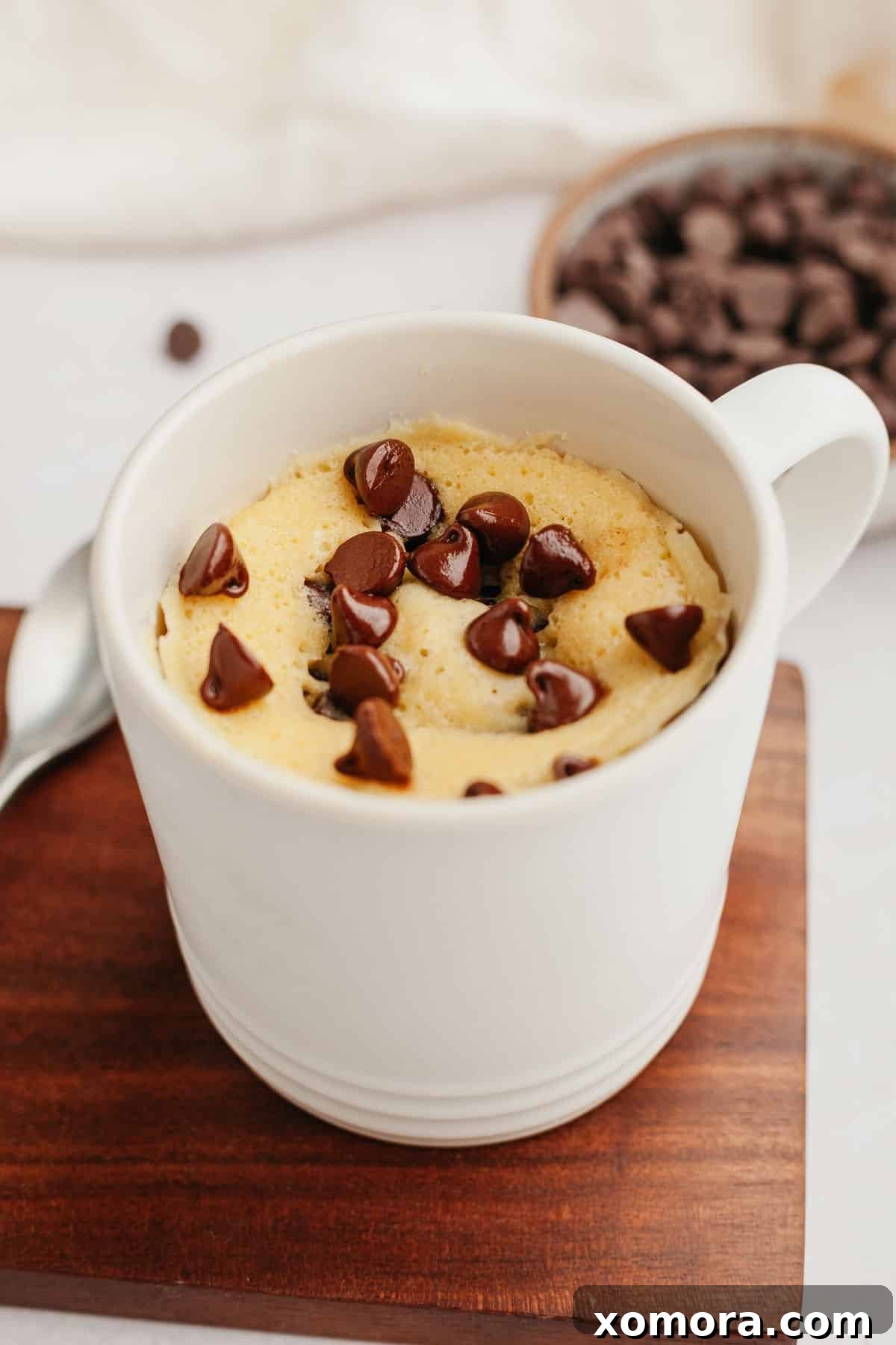 Quick Gluten-Free Chocolate Chip Mug Treat 7 A freshly microwaved gluten-free chocolate chip mug cake, garnished with whipped cream and chocolate shavings.