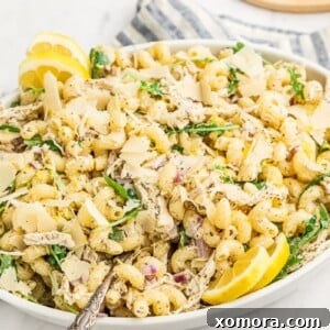 A bowl of creamy lemon pasta salad, garnished with fresh lemon zest and shaved parmesan