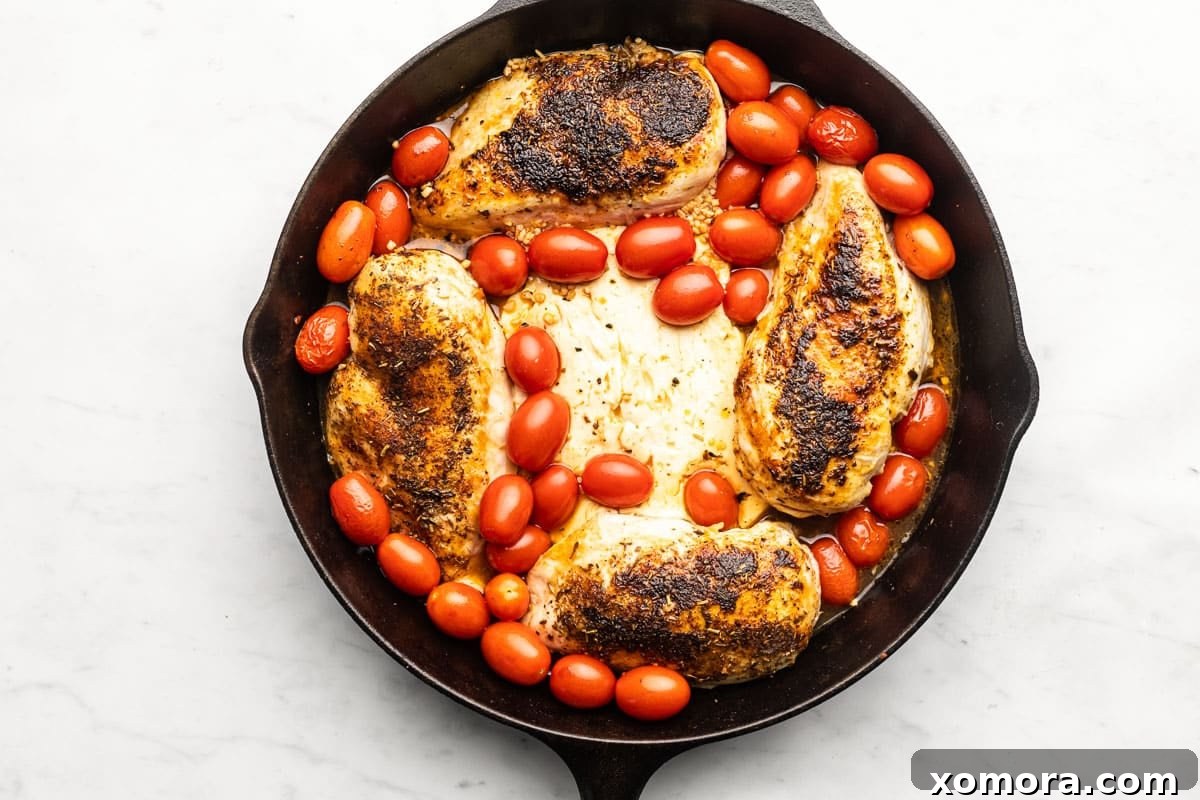 Zesty Feta Chicken Bake 4 Close-up of a block of feta cheese and grape tomatoes in a cast iron skillet, ready for baking.