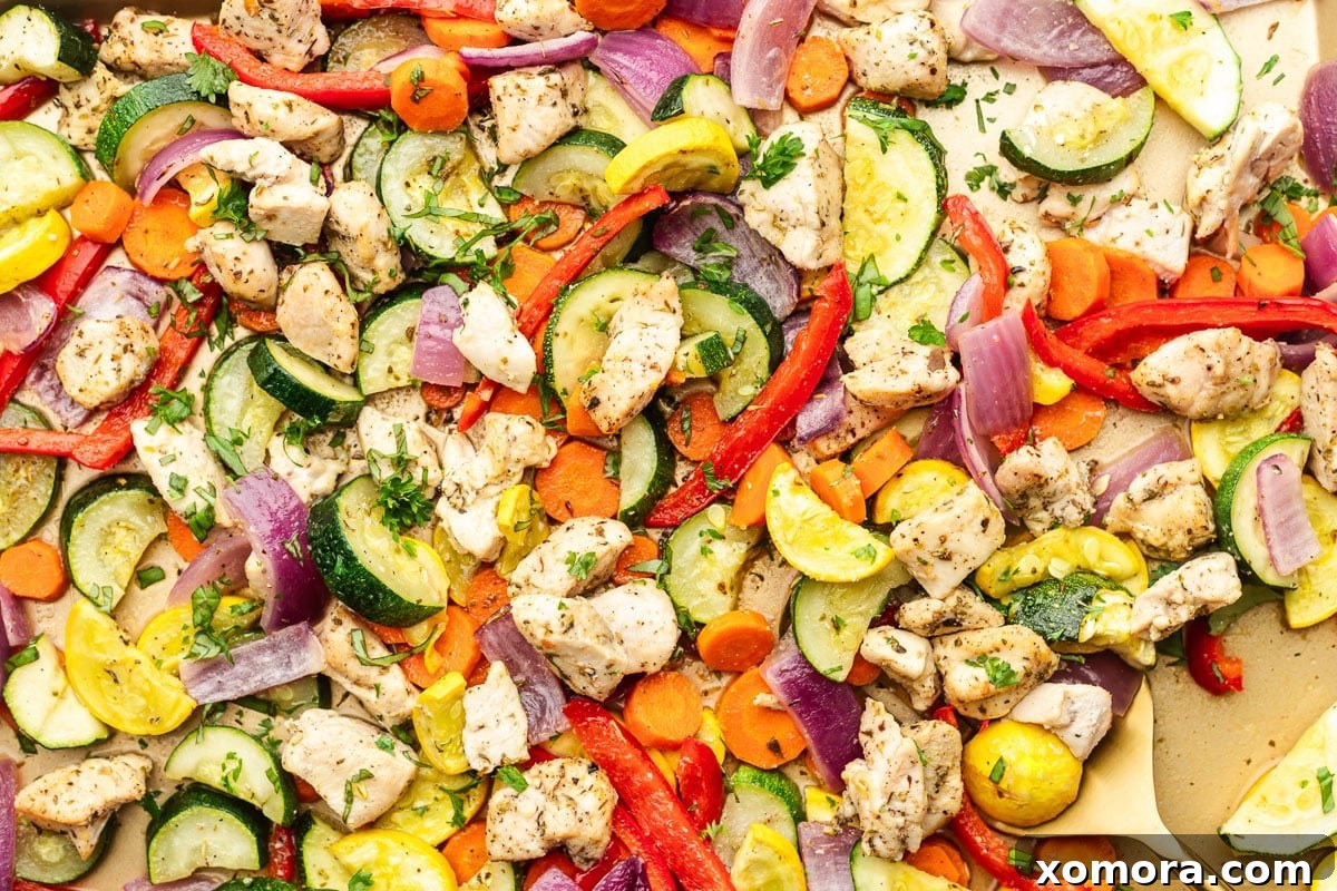 Assorted raw vegetables and chicken breast pieces on a cutting board, ready for preparation.