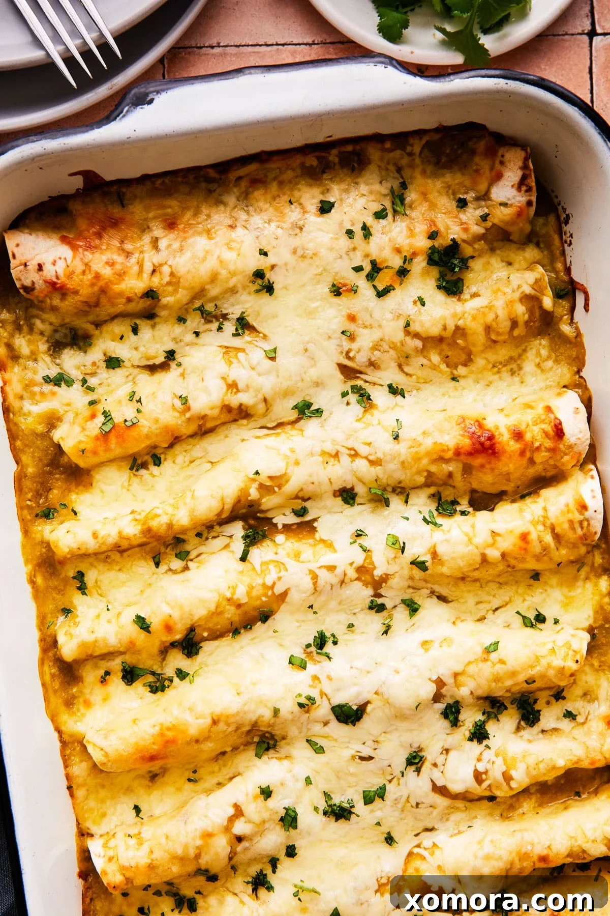 Effortless Green Chile Chicken Enchiladas 5 A single salsa verde chicken enchilada garnished with fresh cilantro and a lime wedge, showcasing its vibrant green sauce and melted cheese.