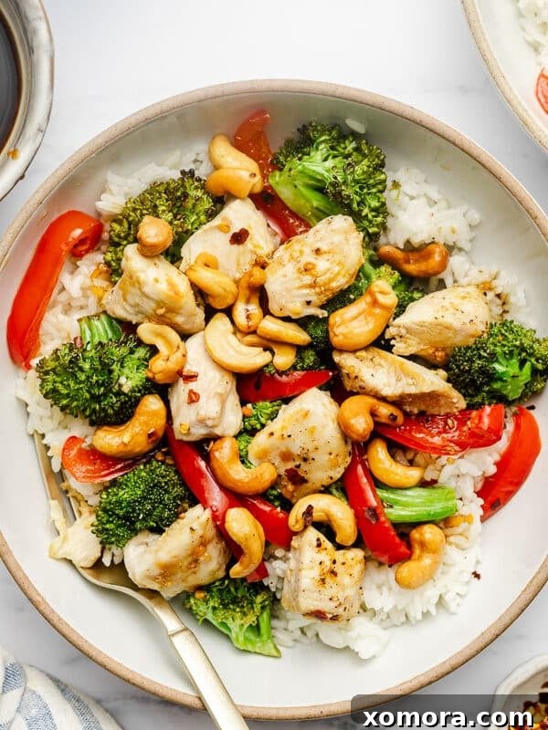 Sheet Pan Cashew Chicken served over rice with colorful vegetables.