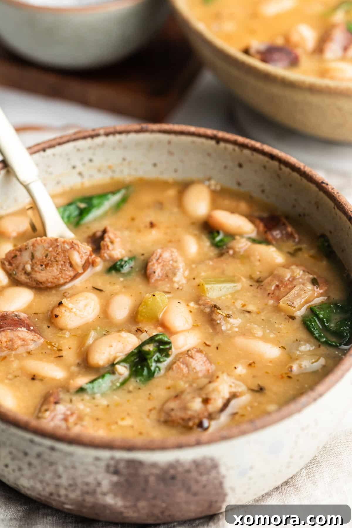 A close-up of the hearty white bean soup with sausage and spinach, showing the creamy texture.