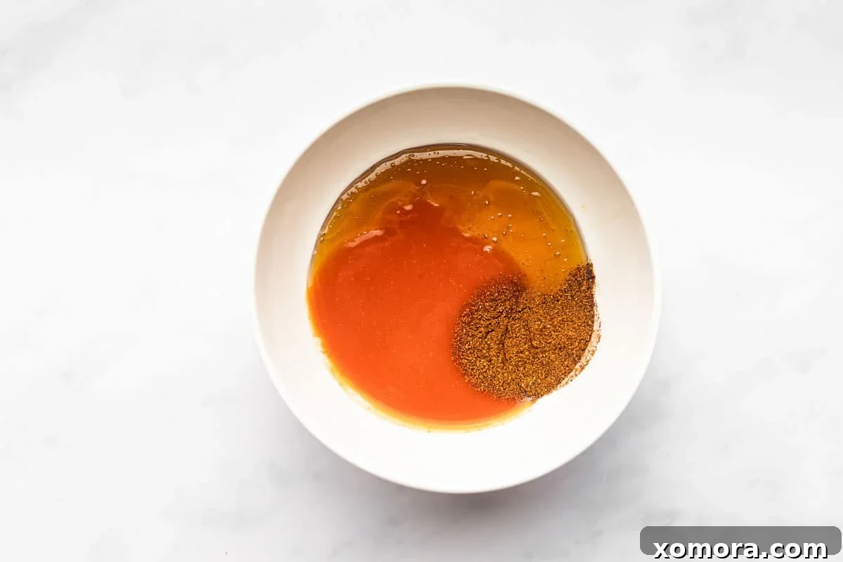 Sweet Heat Honey Drizzle 4 A small bowl of homemade hot honey sauce, with ingredients like honey and hot sauce in the background.