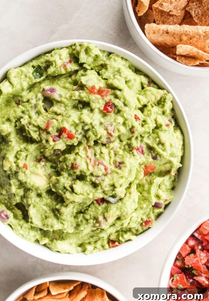 Ingredients for guacamole laid out: ripe avocados, a tomato, an onion, fresh cilantro, and a lime.