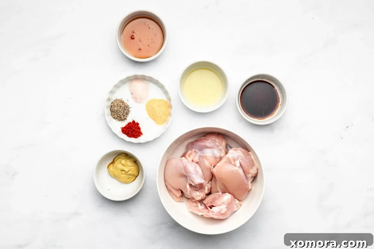 Ingredients for chicken thigh marinade laid out on a wooden cutting board, including honey, dijon mustard, soy sauce, and seasonings.