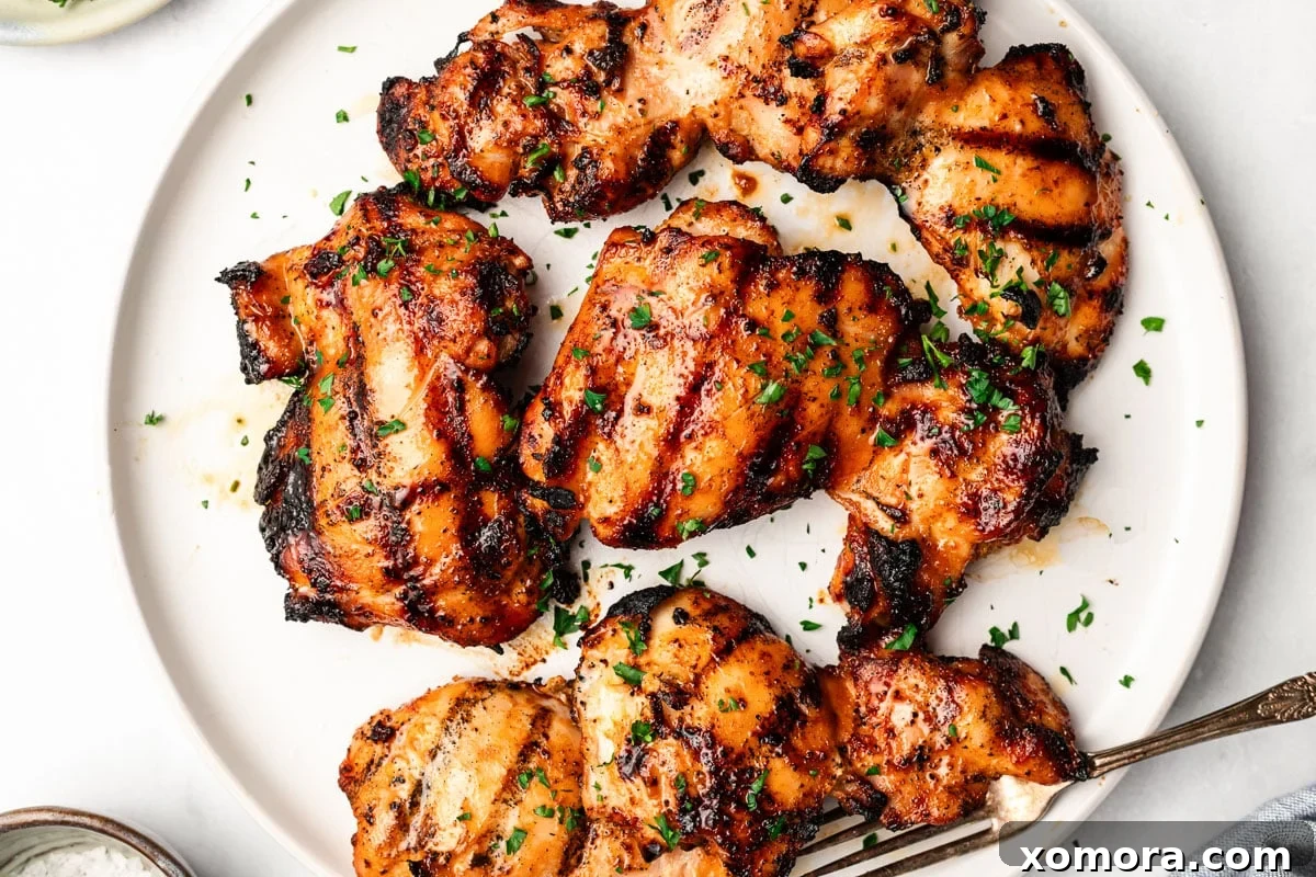 Three marinated chicken thighs cooking on a hot grill with visible flames and smoke, showing excellent char marks.