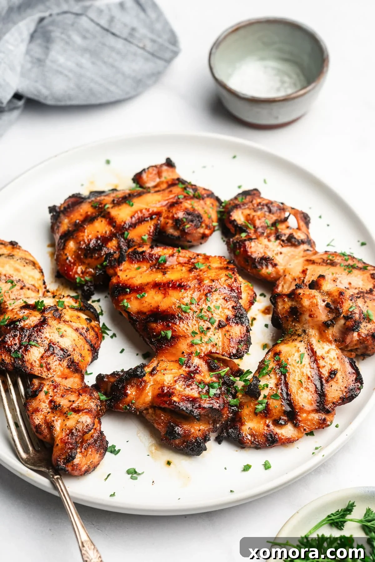 Beautifully plated marinated grilled chicken thighs, garnished with fresh herbs, ready to be served.