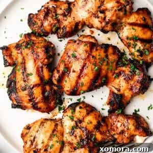 Grilled chicken thighs with a rich marinade, served on a plate.