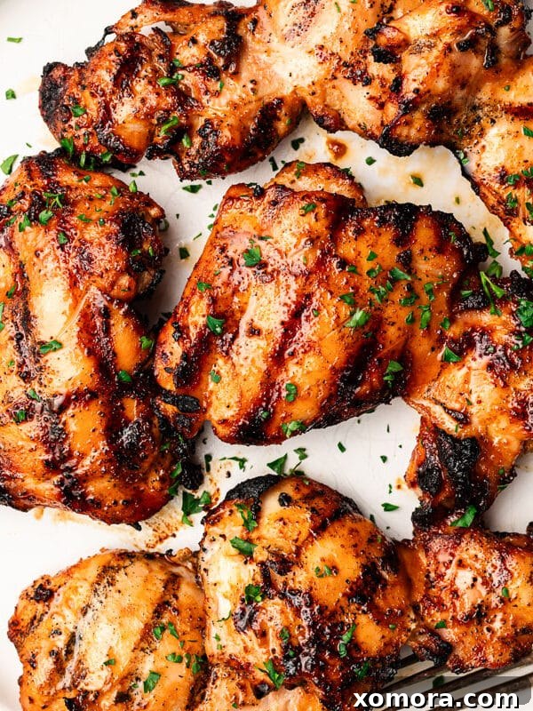 The Best Marinated Grilled Chicken Thighs on a grill, perfectly charred and juicy.