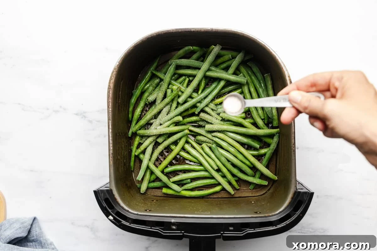 Crispy Air Fryer Frozen Green Beans 4 Serving of air fried frozen green beans in a white bowl with lemon wedges.