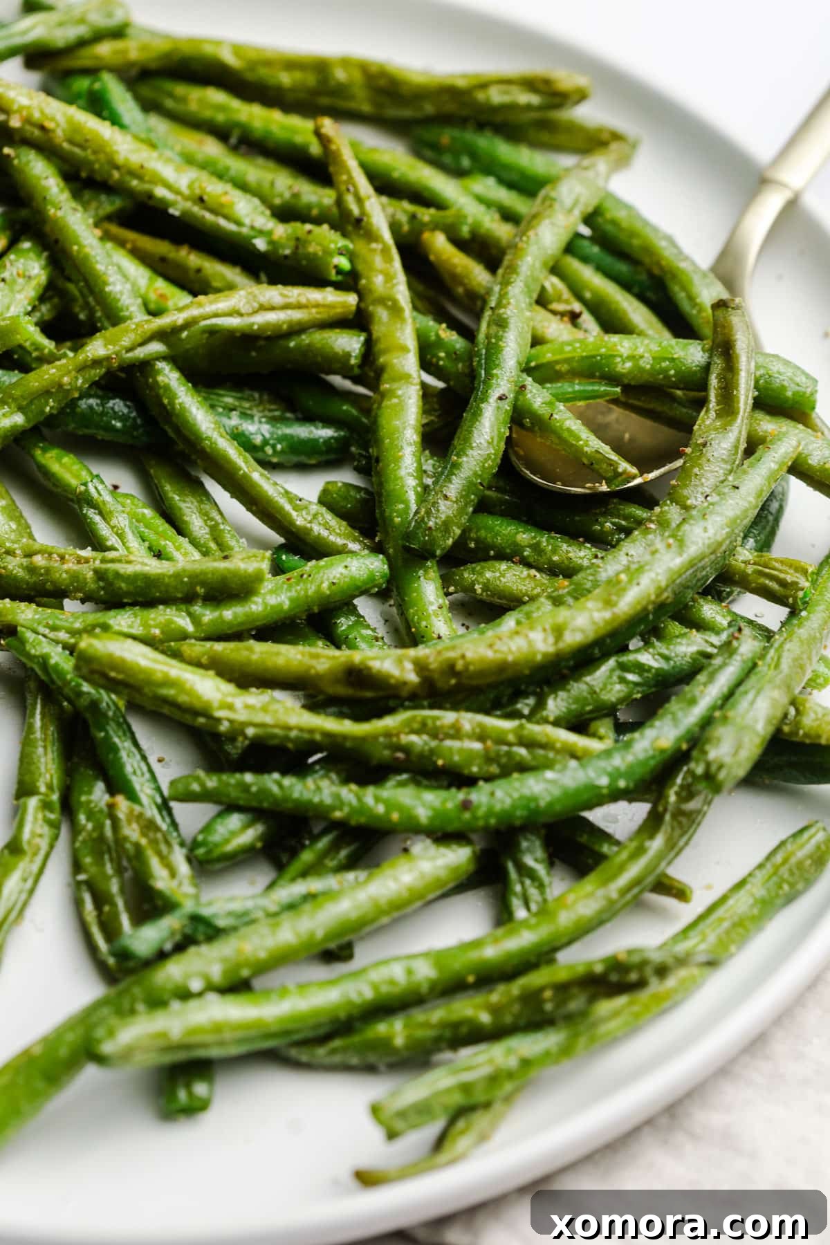 Crispy Air Fryer Frozen Green Beans 6 Air fryer frozen green beans in a white dish, ready to be eaten.