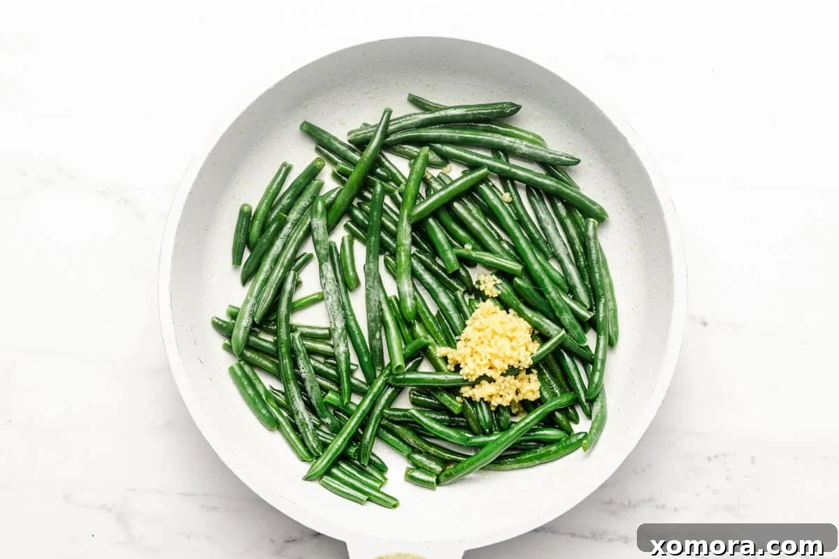 Crisp Garlic Green Beans 5 Sautéed garlic green beans being stirred in a large skillet.