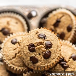 A perfectly golden brown chocolate chip banana oat muffin with a scattering of chocolate chips on top.