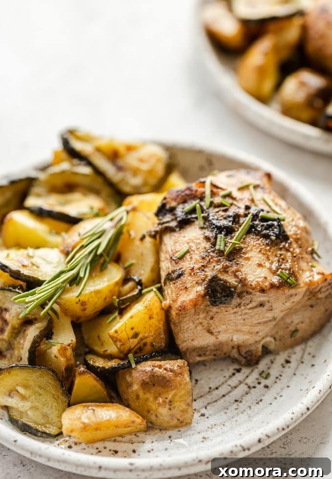 Sheet Pan Chicken with Roasted Potatoes and Zucchini 2 Golden brown sheet pan chicken with roasted potatoes and zucchini, garnished with fresh rosemary.