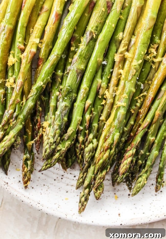 Zesty Roasted Asparagus 2 Freshly roasted asparagus spears with lemon wedges on a white plate