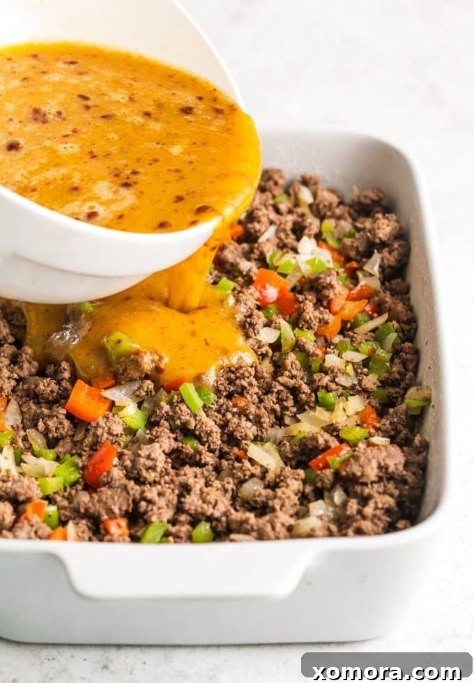 Zesty Plant-Based Mexican Breakfast Bake 4 A raw Dairy-Free Mexican Breakfast Casserole ready for the oven, topped with diced tomatoes and green onions, showing the layered ingredients.