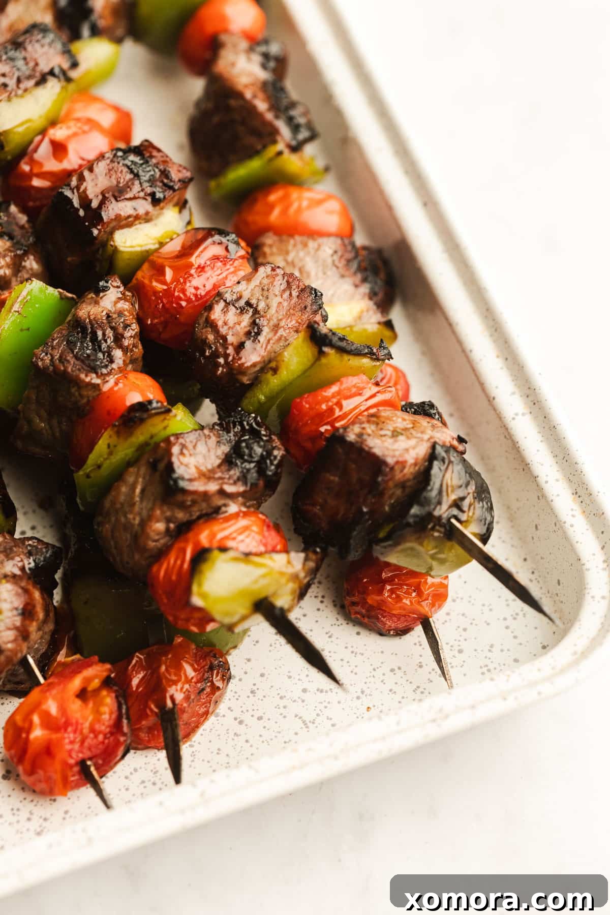 Zesty Pesto Steak Skewers with Charred Garden Vegetables 5 Assortment of grilled steak kabobs on a rustic wooden board.