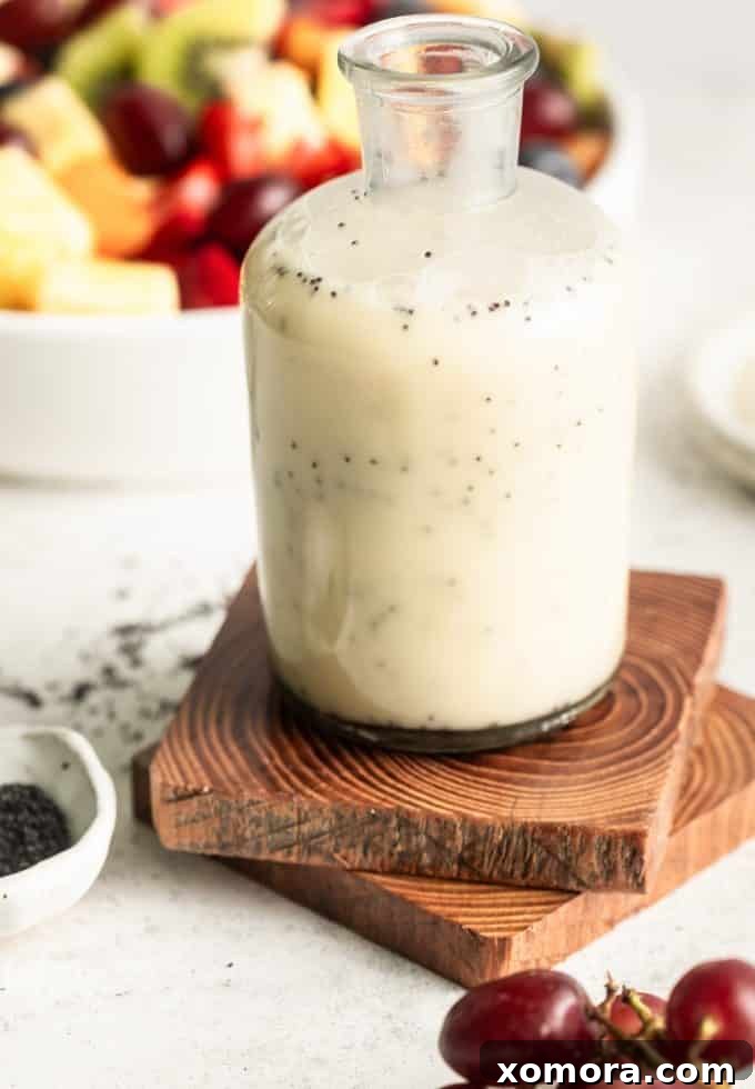 Zesty Lemon Poppy Seed Dressing 2 Bright yellow lemon poppy seed dressing in a glass jar, garnished with fresh lemon slices and poppy seeds.