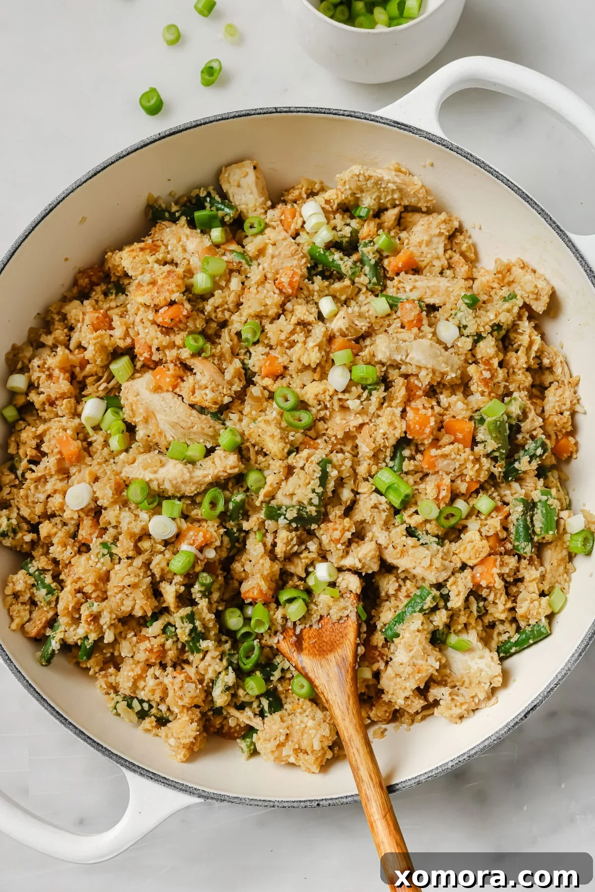 Wholesome Cauliflower Chicken Fried Rice 5 A close-up of a serving of cauliflower chicken fried rice, garnished with fresh green onions, showcasing the vibrant colors and appealing texture.