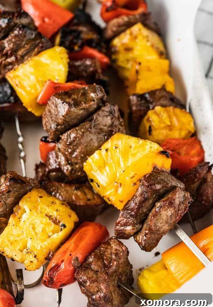 Aloha Grilled Steak Kabobs 3 Marinated steak chunks, pineapple pieces, and colorful mini peppers waiting to be threaded onto skewers for Hawaiian kabobs.