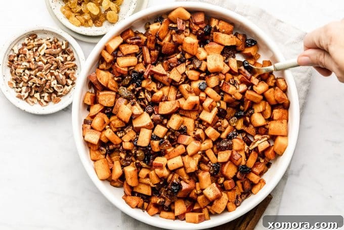Finished Cinnamon Raisin Diced Sweet Potatoes in a bowl with a spoon