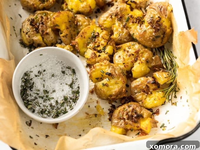 Crispy Rosemary Garlic Smashed Potatoes 4 Ingredients for rosemary garlic smashed potatoes laid out: potatoes, garlic, rosemary, olive oil, butter, salt, pepper.