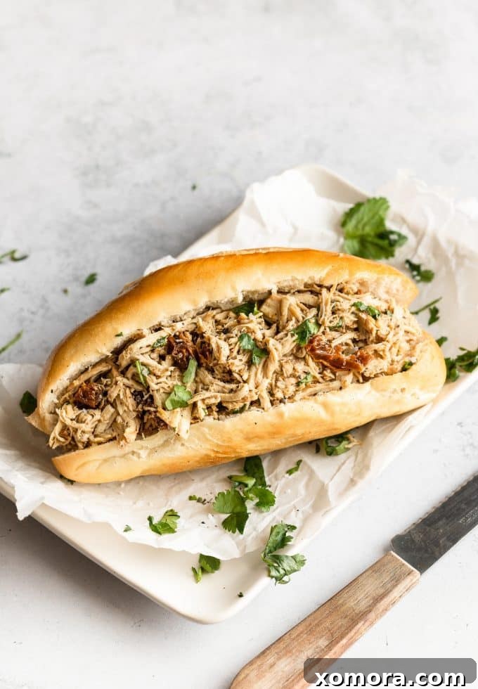 Fork-Tender Slow Cooker Italian Shredded Chicken 4 A bowl of Slow Cooker Italian Shredded Chicken ready to be served, garnished with fresh herbs.
