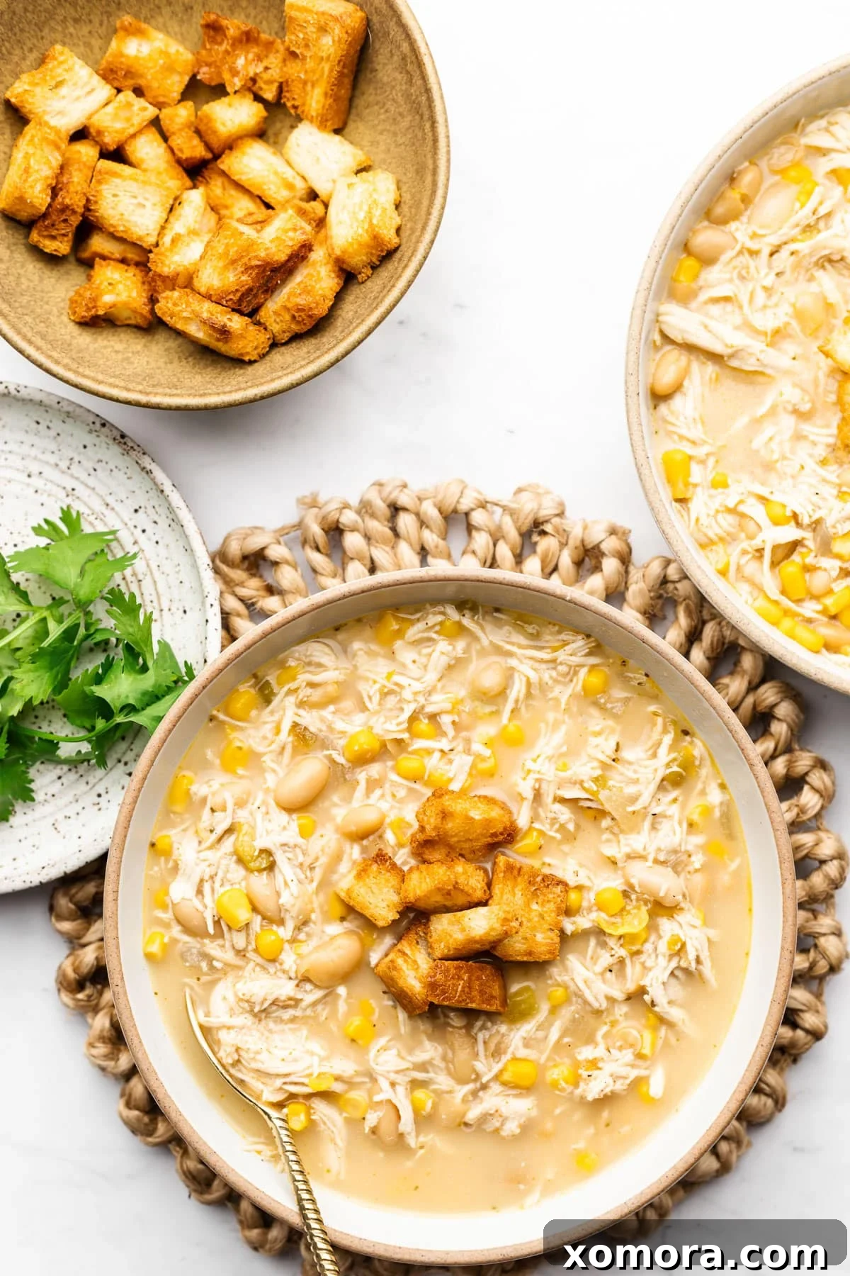 Overhead shot of Slow Cooker White Chicken Chili garnished with a variety of toppings like cheese, cilantro, and sour cream.