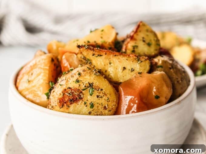Roasted apples and potatoes scattered on a large sheet pan, ready to serve.