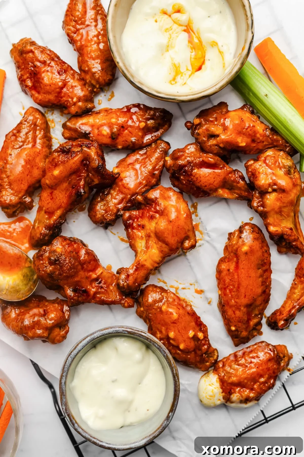 Zesty Oven-Baked Buffalo Wings 2 Crispy baked buffalo chicken wings ready to be served on a platter with ranch dressing, celery, and carrots.