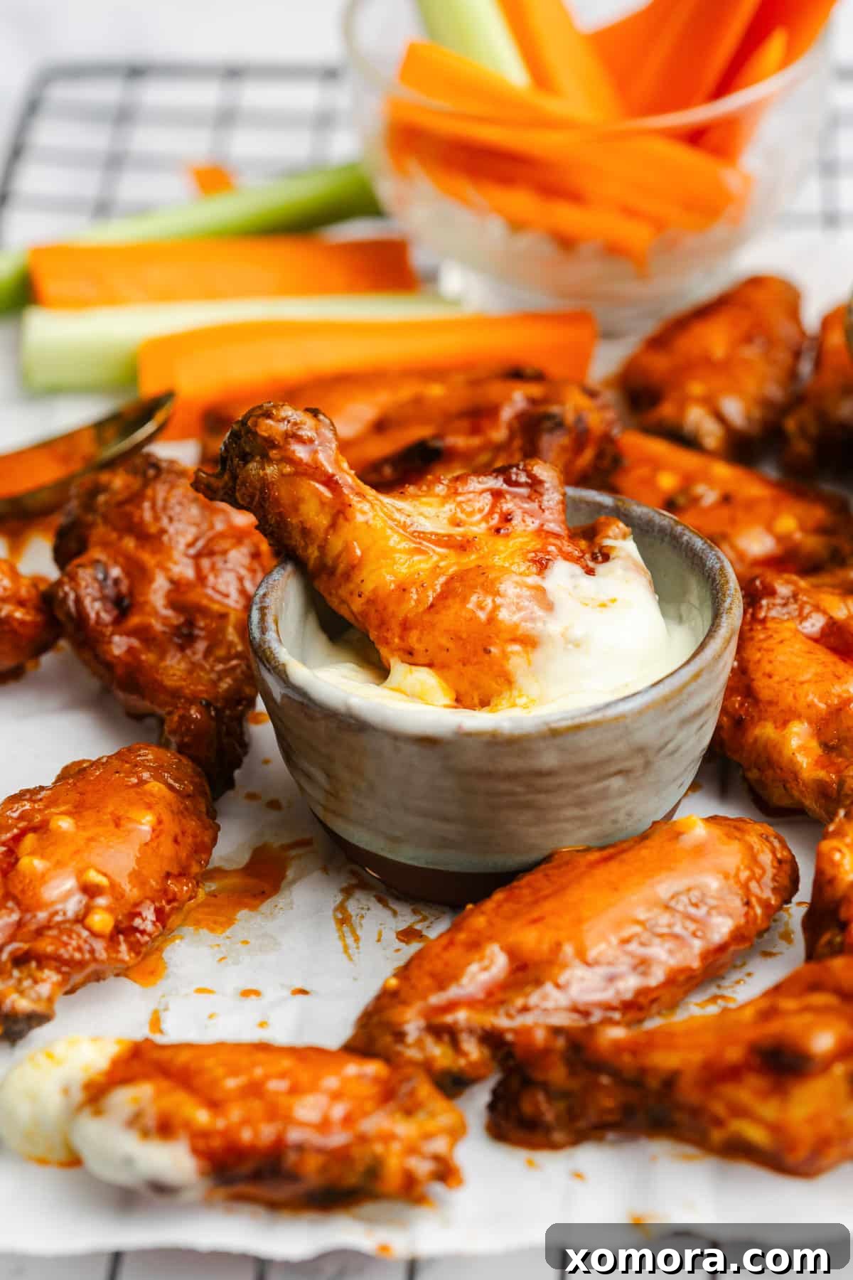 Zesty Oven-Baked Buffalo Wings 5 Baked buffalo chicken wings being tossed in a large bowl with the homemade sauce.