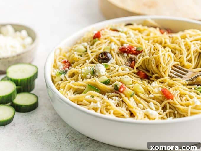 Vibrant 20-Minute Greek Pasta Salad 4 Ingredients for Greek pasta salad laid out on a kitchen counter: angel hair pasta, various chopped vegetables, feta, and dressing components.