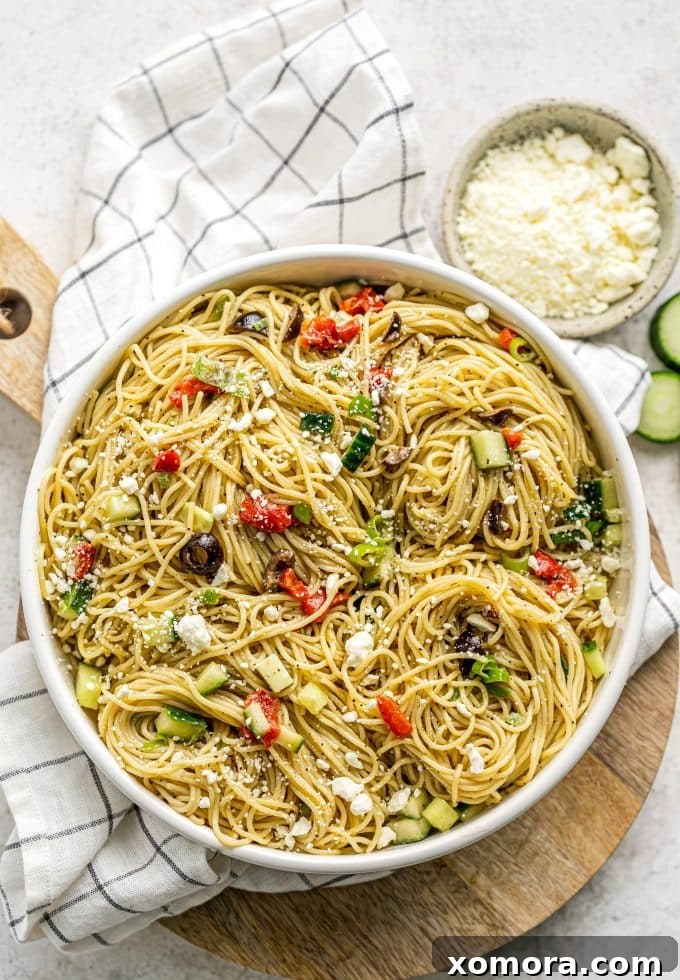 Vibrant 20-Minute Greek Pasta Salad 5 A large serving spoon scooping a portion of Greek pasta salad from a bowl, showcasing its colorful ingredients.